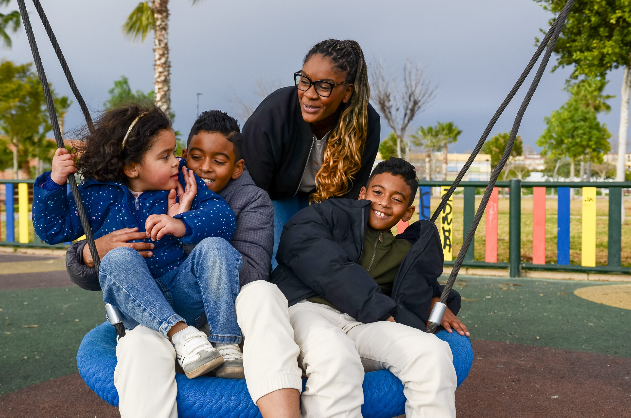 Happy family having fun on a swing at the playground